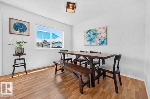 Bright dining area featuring wood-finish flooring, a contemporary ceiling light fixture, and a large window providing natural light - 17411 90 Street Nw, Edmonton, AB - Indoor Photo Showing Dining Room