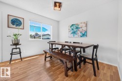 Bright dining area featuring wood-finish flooring, a contemporary ceiling light fixture, and a large window providing natural light - 