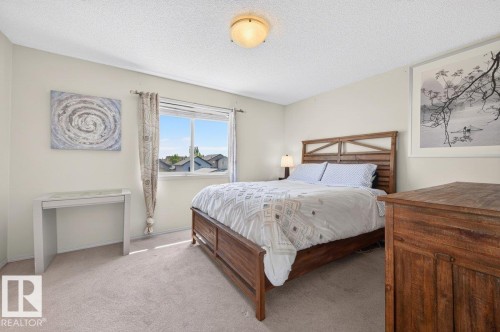 Carpeted bedroom with a large window, a wood-finish bed frame, and a flush-mount ceiling light - 17411 90 Street Nw, Edmonton, AB - Indoor Photo Showing Bedroom