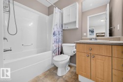 Full bathroom featuring a single-piece bathtub and shower surround, a light wood-finish vanity with a light-toned countertop, and a wall-mounted medicine cabinet - 