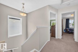 Upper-level hallway featuring neutral-toned walls, recessed lighting, and a pendant light fixture - 