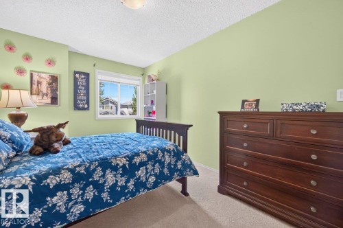 Bright room featuring a large window, light green wall finishes, and a textured ceiling - 17411 90 Street Nw, Edmonton, AB - Indoor Photo Showing Bedroom