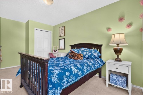 Bedroom featuring carpet flooring, painted walls, and a built-in closet with bi-fold doors - 17411 90 Street Nw, Edmonton, AB - Indoor Photo Showing Bedroom