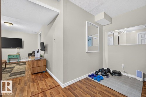 Wood-finish flooring throughout, complemented by light-toned walls and crisp white trim - 17411 90 Street Nw, Edmonton, AB - Indoor Photo Showing Other Room