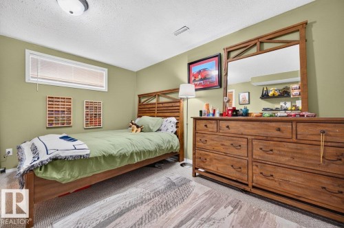 Carpeted room featuring a wooden bed frame, a high horizontal window with blinds, and a built-in ceiling light fixture - 17411 90 Street Nw, Edmonton, AB - Indoor Photo Showing Bedroom