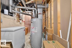 Utility area featuring a water heater, exposed ductwork, and unfinished wall studs - 