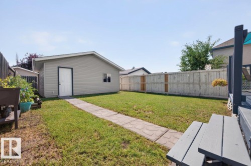 Rear yard featuring a detached auxiliary building with siding, a paved walkway, and a privacy fence - 17411 90 Street Nw, Edmonton, AB - Outdoor With Exterior