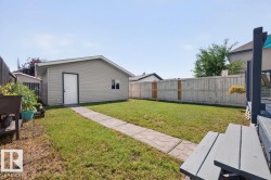 Rear yard featuring a detached auxiliary building with siding, a paved walkway, and a privacy fence - 