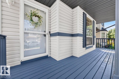 Inviting front porch featuring blue-painted wood decking, white siding, and a white storm door - 17411 90 Street Nw, Edmonton, AB - Outdoor With Deck Patio Veranda With Exterior