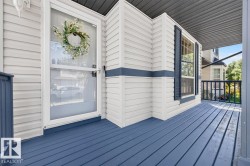 Inviting front porch featuring blue-painted wood decking, white siding, and a white storm door - 