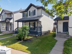 Two-story residence featuring light-colored siding, dark trim, and a covered front porch - 
