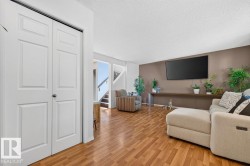 Living area featuring wood-finish flooring, a neutral color palette, and a built-in wall shelf - 