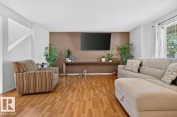 Spacious living area featuring wood-finish flooring, a feature wall, and a large window with white drapery - 