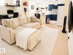 Open-concept living space featuring wood-finish flooring, a kitchen with blue cabinetry, a white countertop, and a built-in breakfast bar - 