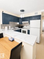 Kitchen featuring dark blue cabinetry, white countertops, stainless steel sink, and mosaic tile backsplash - 