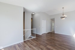 Spacious interior featuring wood-finish flooring, light grey wall paint, and white baseboards - 