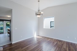 Open-concept room featuring wood-finish flooring, vaulted ceiling, and a prominent chandelier - 