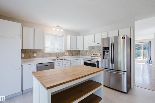 Kitchen featuring white cabinetry, stone backsplash, and stainless steel appliances - 337 Pearson Crescent Nw, Edmonton, AB - Indoor Photo Showing Kitchen With Double Sink With Upgraded Kitchen
