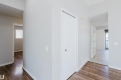 Interior hallway featuring wood-finish flooring, light grey walls, and white trim - 