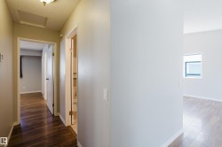 Interior hallway featuring wood-finish flooring, light-toned walls, and white trim - 