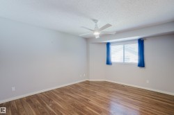 Spacious room featuring wood-finish flooring, light grey walls, and a multi-pane window - 
