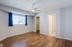 Spacious room featuring wood-finish flooring, a contemporary ceiling fan with integrated lighting, and a large window - 