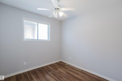 Room featuring wood-finish flooring, a white ceiling fan, and a window with horizontal blinds - 