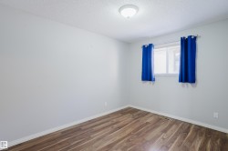 Room featuring wood-finish flooring, light grey walls, and a white ceiling with a flush-mount light fixture - 