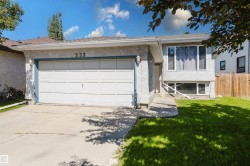 Stucco exterior featuring a two-car garage with overhead door, concrete driveway, and front lawn - 