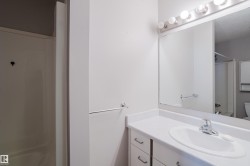 Bathroom featuring a single vanity with built-in sink, chrome faucet, wall-mounted mirror, and vanity lighting fixture - 