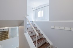 Multi-level interior featuring a staircase with wood-finish treads and white risers, white railing with vertical balusters, and light gray wall paint - 