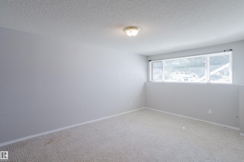 Spacious room featuring light gray walls, textured ceiling, and light-colored patterned carpeting - 337 Pearson Crescent Nw, Edmonton, AB - Indoor Photo Showing Other Room