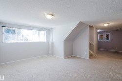 Spacious interior room featuring light-colored walls, textured carpeting, and a large multi-pane window - 