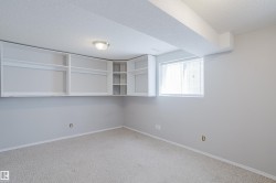 Room with light gray walls, built-in white shelving, and a single window with blinds - 