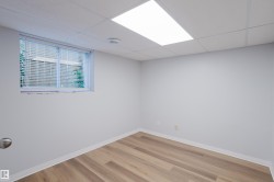 Interior room featuring wood-finish flooring, white baseboards, a drop ceiling with recessed lighting, and a window with horizontal blinds - 
