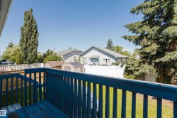 Deck with blue-painted wood railing and steps, overlooking a fenced backyard with green lawn - 