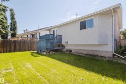 Expansive green yard featuring a privacy fence, an exterior staircase with railings, and a stucco exterior - 