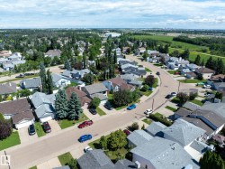 Aerial perspective showcasing an established residential neighborhood with detached homes, mature trees, and paved streets - 