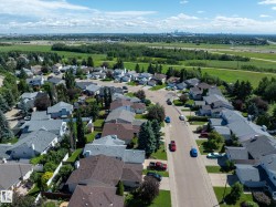 Aerial perspective of a residential neighborhood with a variety of single-family homes, mature trees, and paved streets - 
