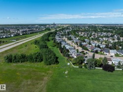 Expansive green space bordering a residential area featuring numerous homes with varied rooflines - 