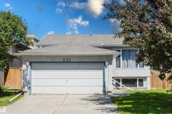 Stucco exterior with a two-car garage, concrete driveway, and mature landscaping - 