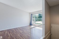 Spacious room with wood-finish flooring, a large picture window, and neutral wall tones - 
