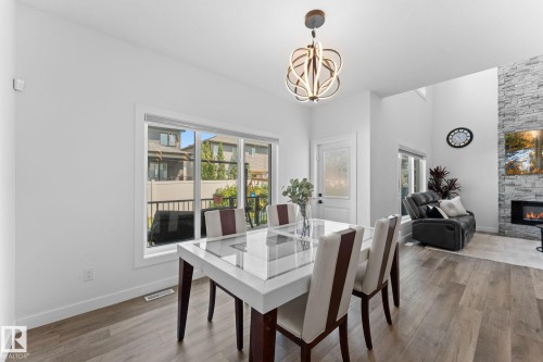 Bright dining area with wood-finish flooring, a contemporary chandelier, and a large window - 59 Willow Link, Fort Saskatchewan, AB - Indoor Photo Showing Dining Room With Fireplace