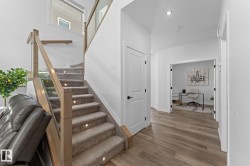 Carpeted staircase with integrated step lighting and wood-finish railing with glass panels - 