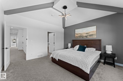 Vaulted ceiling featuring exposed beams, recessed lighting, a modern chandelier, and plush carpeting - 59 Willow Link, Fort Saskatchewan, AB - Indoor Photo Showing Bedroom