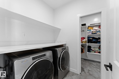 Functional utility space featuring a white countertop with integrated backsplash, an upper storage shelf, and a separate closet with built-in shelving - 59 Willow Link, Fort Saskatchewan, AB - Indoor Photo Showing Laundry Room