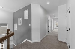 Hallway featuring recessed lighting, a neutral gray wall with three integrated display niches, and white trim - 