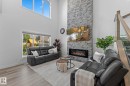 Living area featuring a floor-to-ceiling stacked stone fireplace, linear electric insert, and wood-finish flooring - 59 Willow Link, Fort Saskatchewan, AB  - Indoor Photo Showing Living Room With Fireplace 