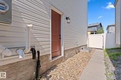 White vinyl siding exterior with a brown entry door, accompanied by an outdoor wall lantern - 