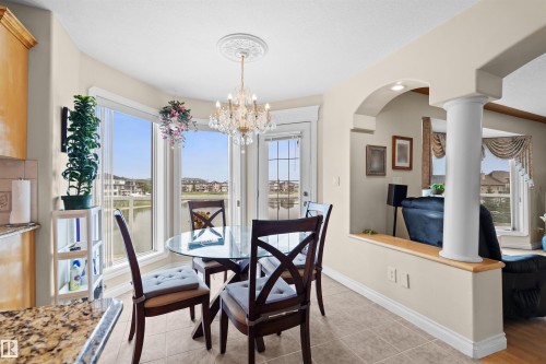 Bay window dining area with a chandelier, tile flooring, and exterior access - 7622 168A Avenue, Edmonton, AB - Indoor Photo Showing Dining Room